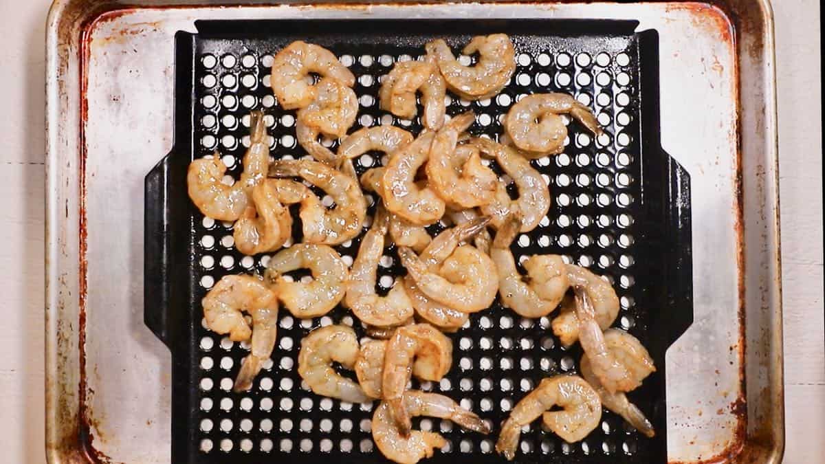 A grill pan topped with raw shrimp.