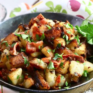Crispy fried potatoes in a skillet topped with bacon.