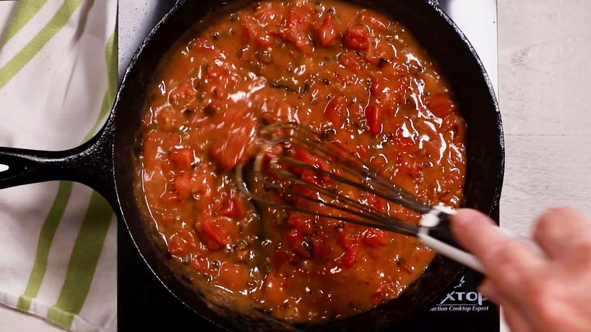 Tomato gravy cooking in a cast-iron skillet.