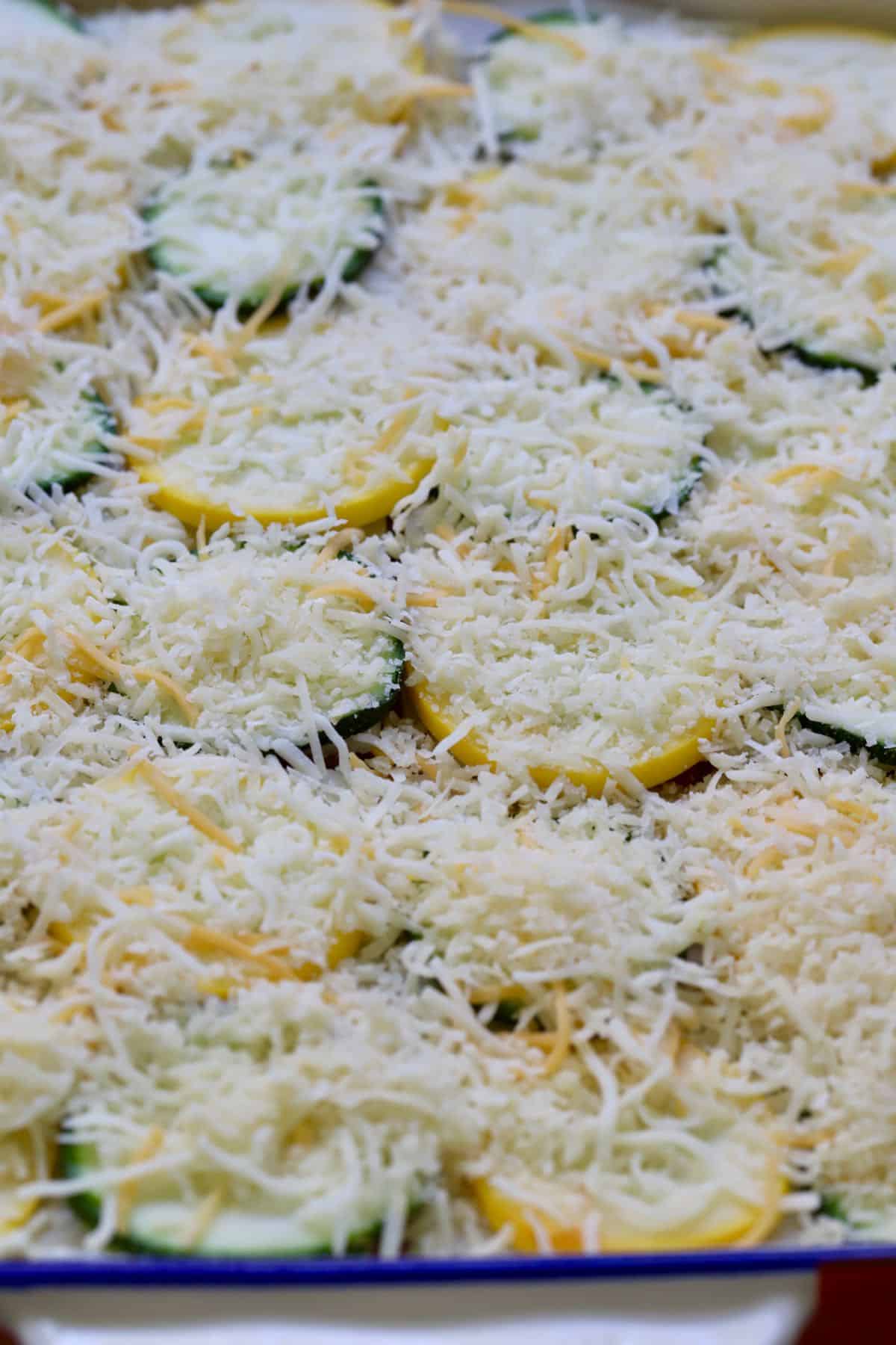 Mozzarella and parmesan cheeses covering slices of squash. 