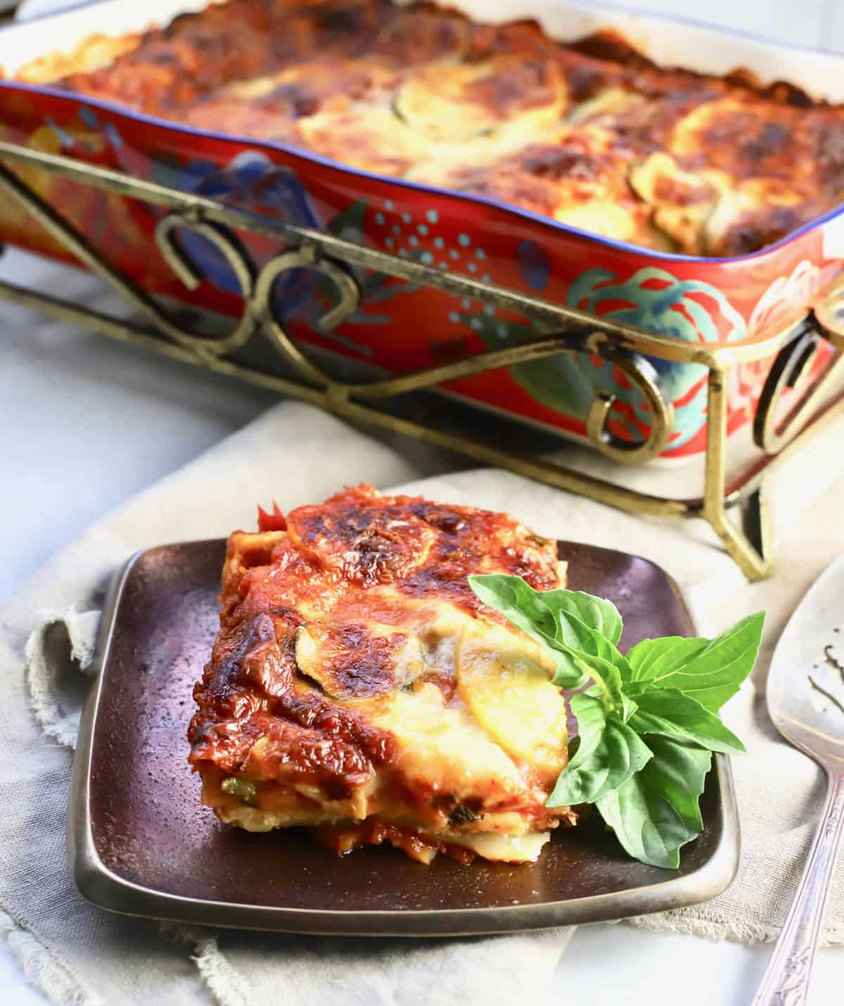 A pan of baked vegetable lasagna with a serving cut out. 