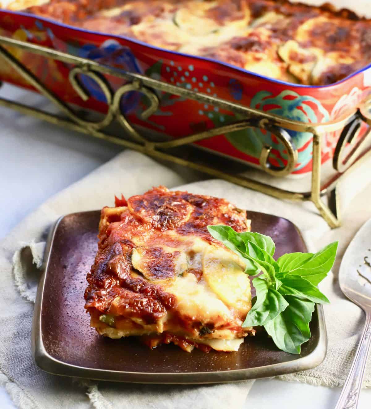 A serving of vegetable lasagna on a bronze plate. 