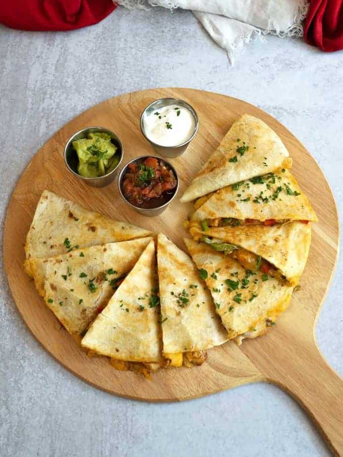 Chicken Fajita Quesadilla sliced on a wooden cutting board. 