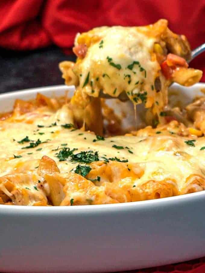 Southwestern chicken pasta topped with cheese in a white baking dish. 