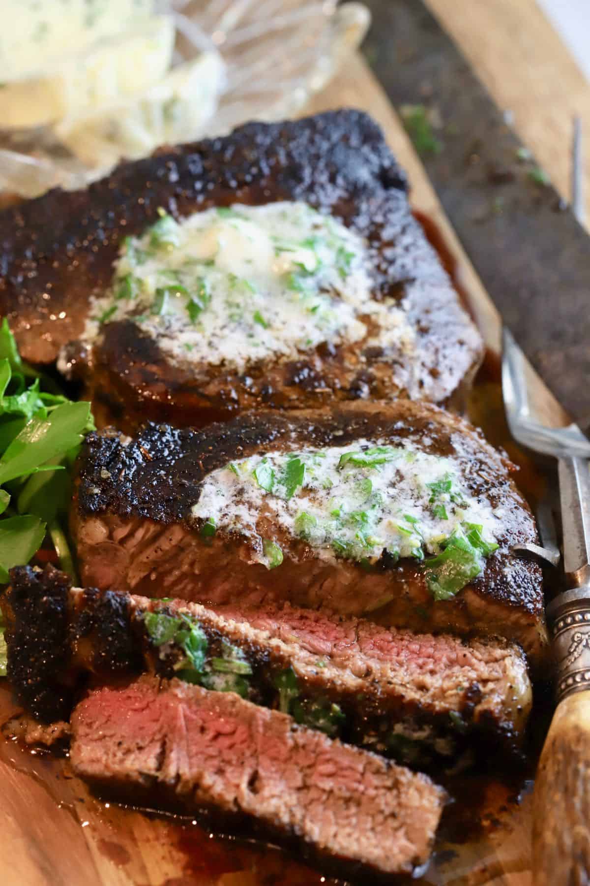 Two blackened steaks topped with garlic herb butter and sliced. 