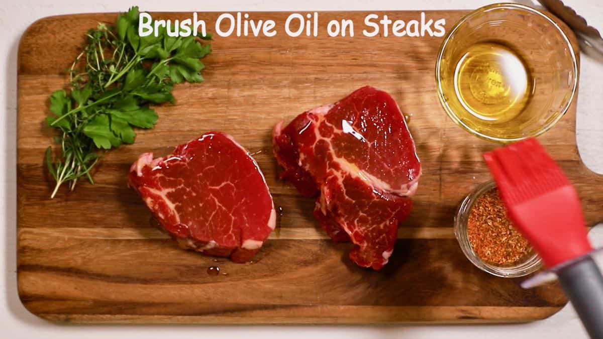 Brushing olive oil on filet mignons.