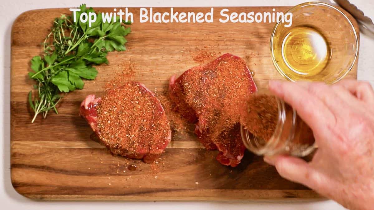 Adding blackened seasoning to two filet mignons. 