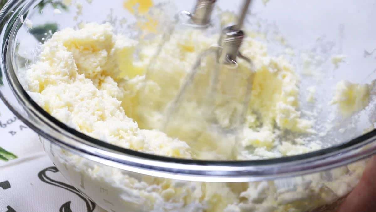 Butter and sugar in a glass bowl with an electric mixer. 