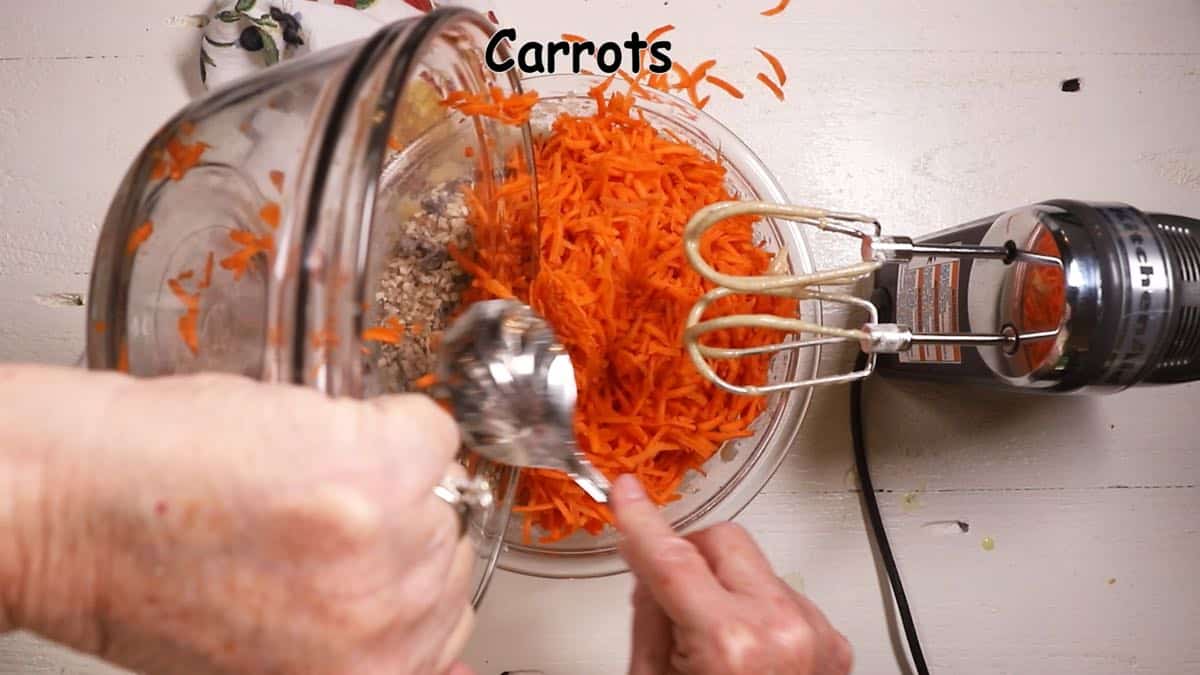 Adding shredded carrots to cake batter. 