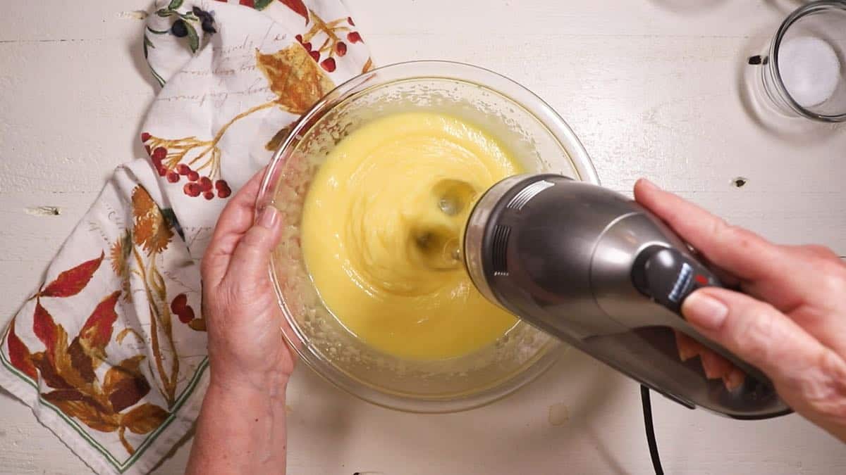 Mixing sugar, oil and eggs in a clear glass bowl. 