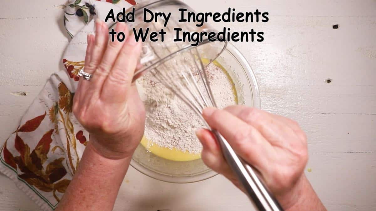 Adding flour to sugar, eggs and oil in a clear glass bowl.