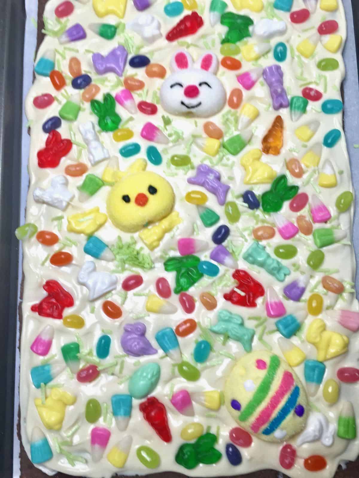 A baking sheet full of white chocolate bark topped with Easter candy. 