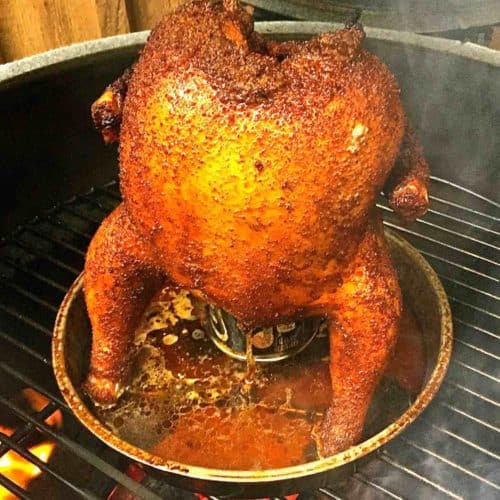 Beer can chicken sitting on a can of beer on a Big Green Egg grill.