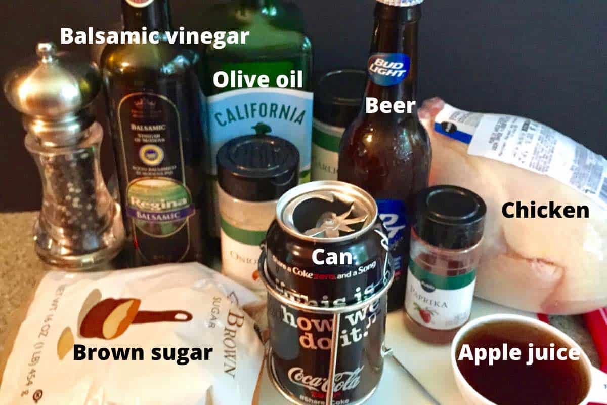 A soda can, a beer, olive oil, balsamic vinegar and brown sugar on a kitchen counter.