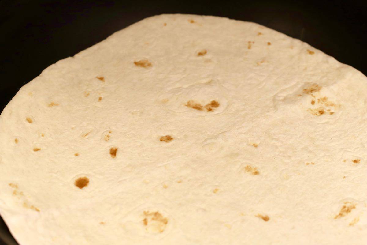 A flour tortilla in a skillet.