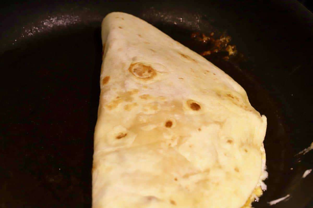 A shrimp quesadilla cooking in a skillet.