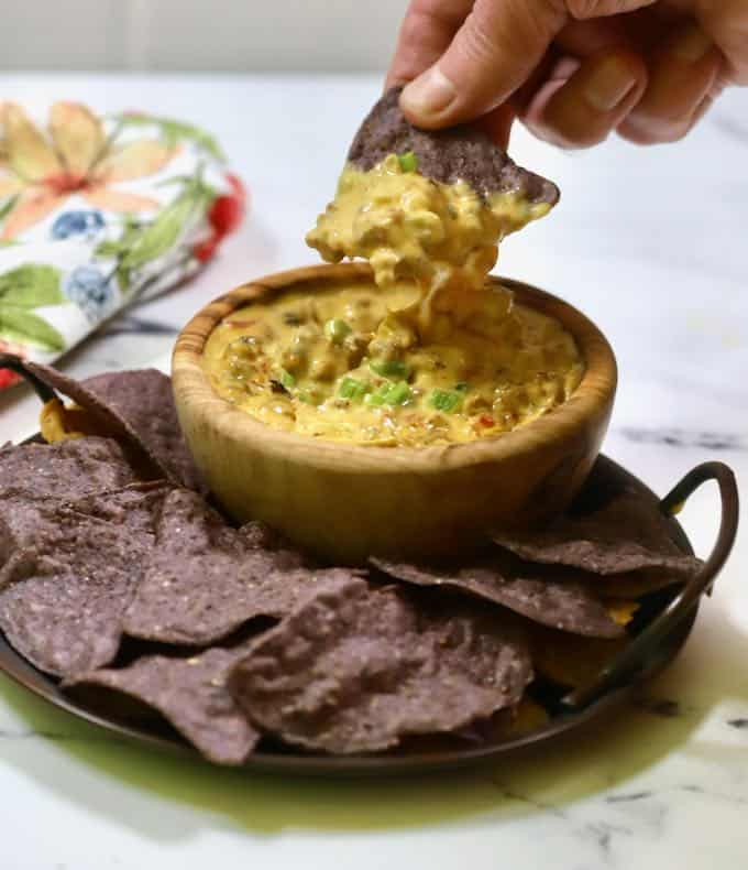 A woodden bowl with smoked queso dip. 