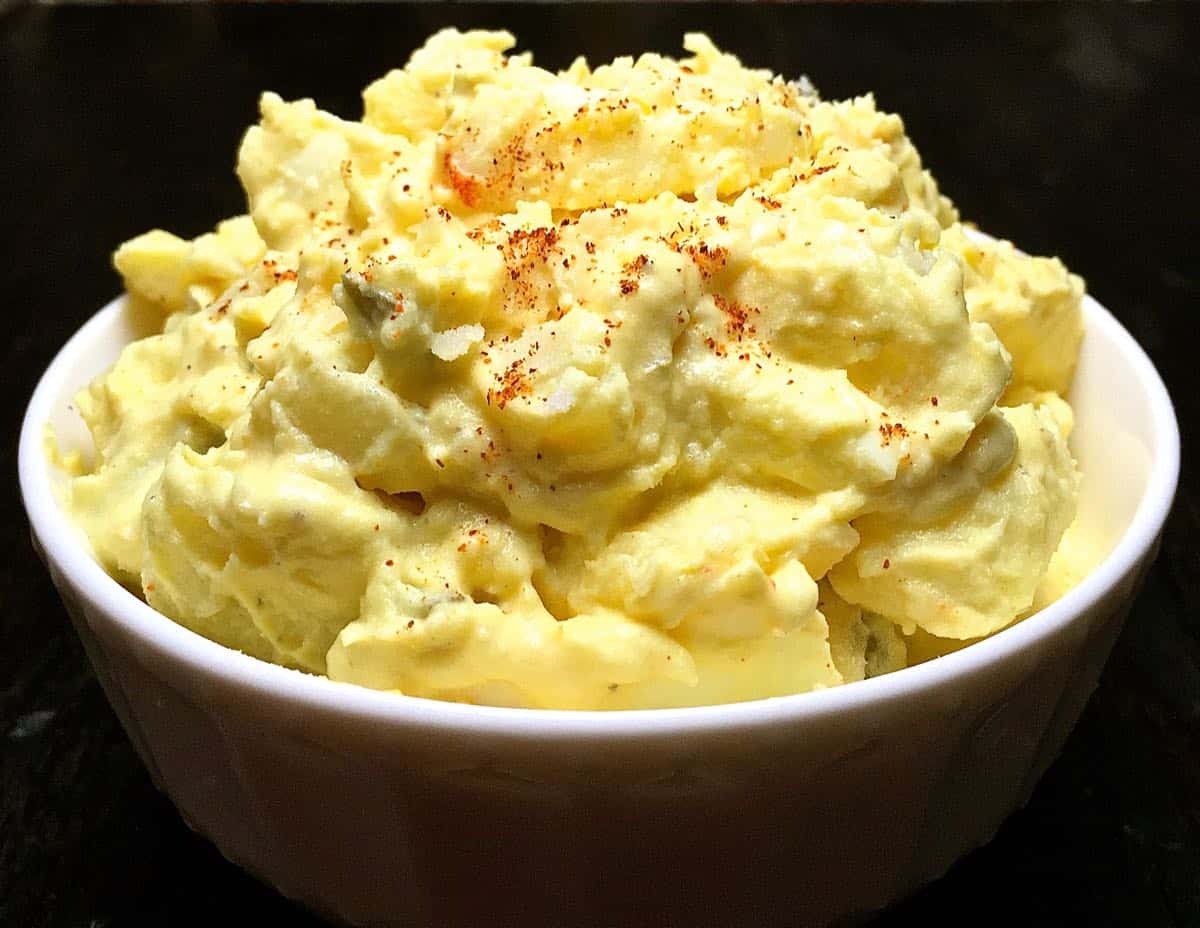 Southern potato salad in a white bowl topped with paprika.