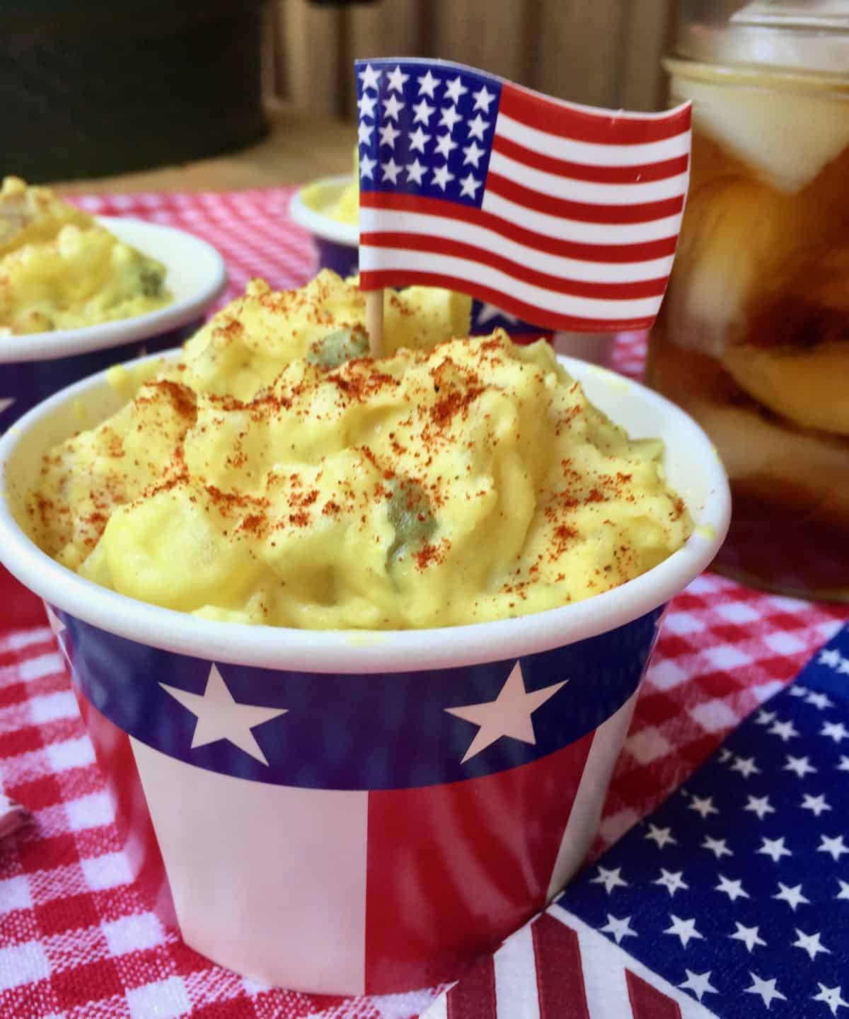 A red, white, and blue bowl full of potato salad.