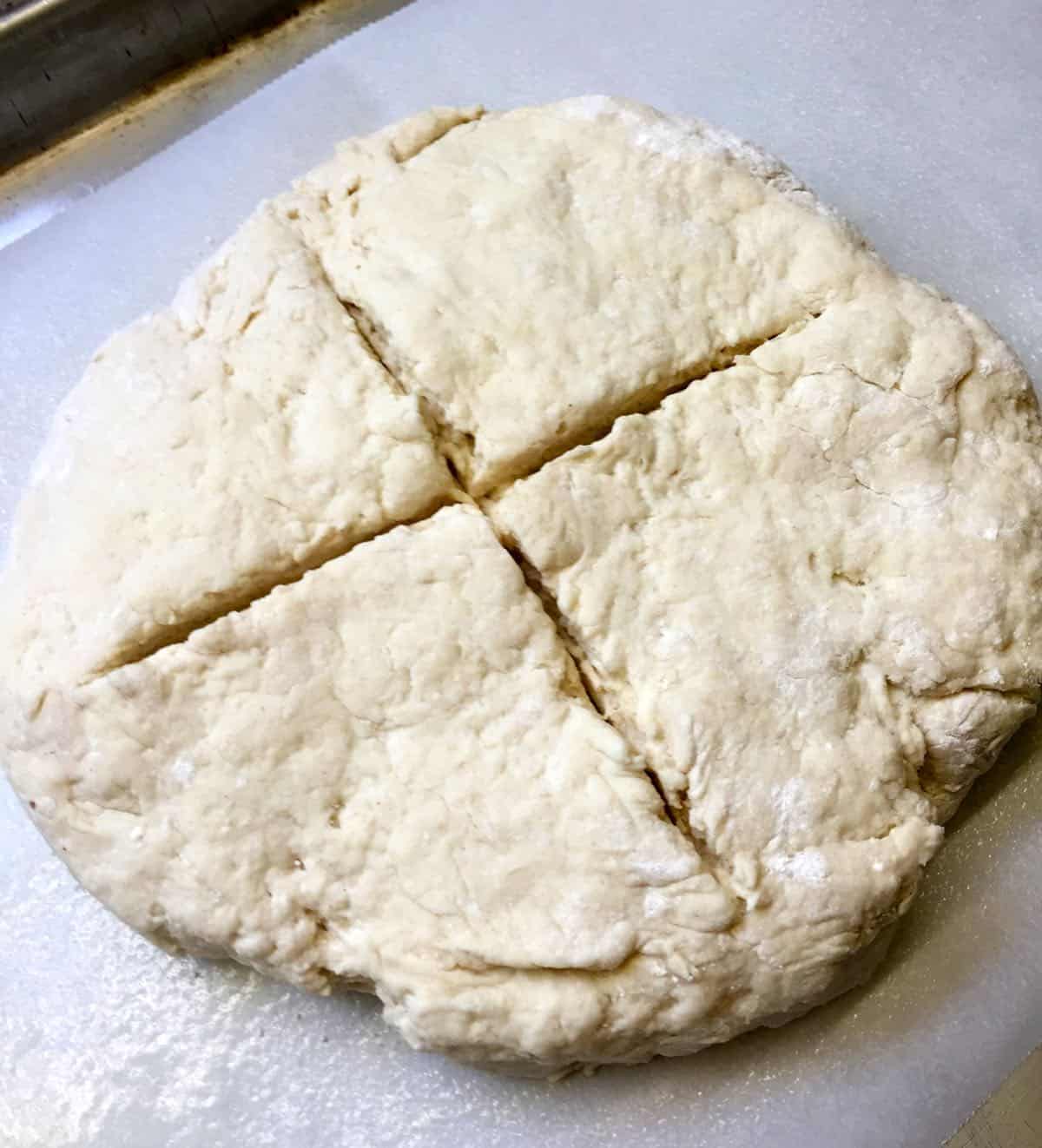 Soda bread dough with a cross cut into the top of it.