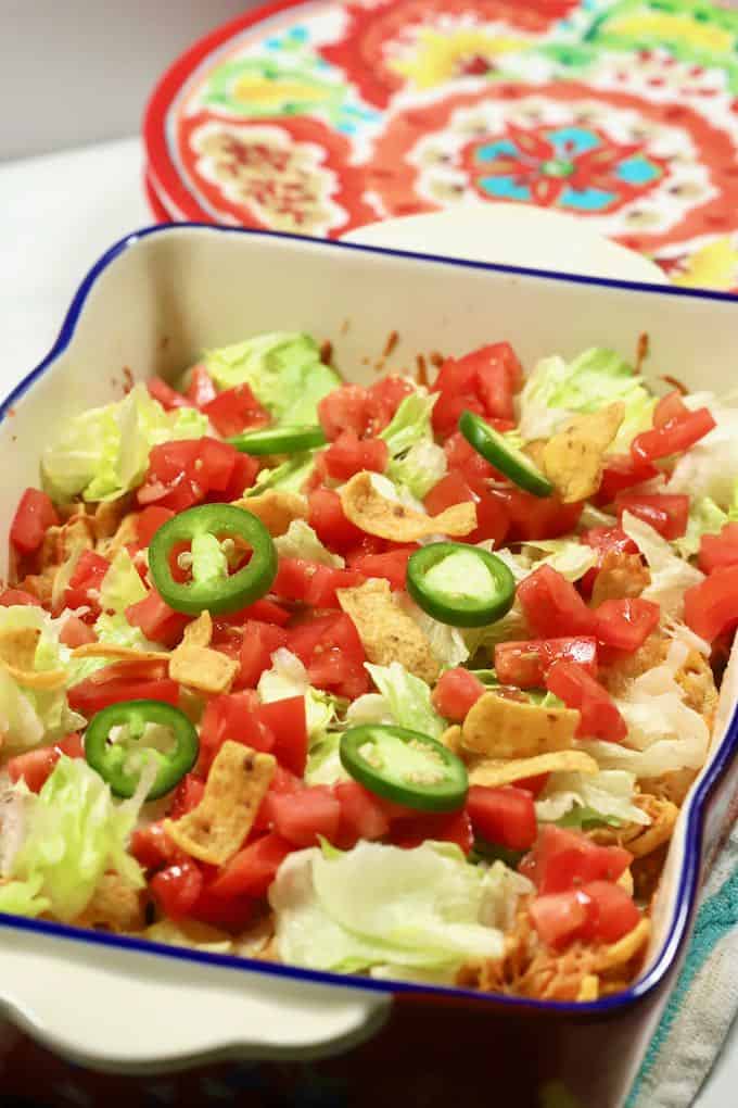 A brightly colored baking dish full of Walking Taco Casserole.