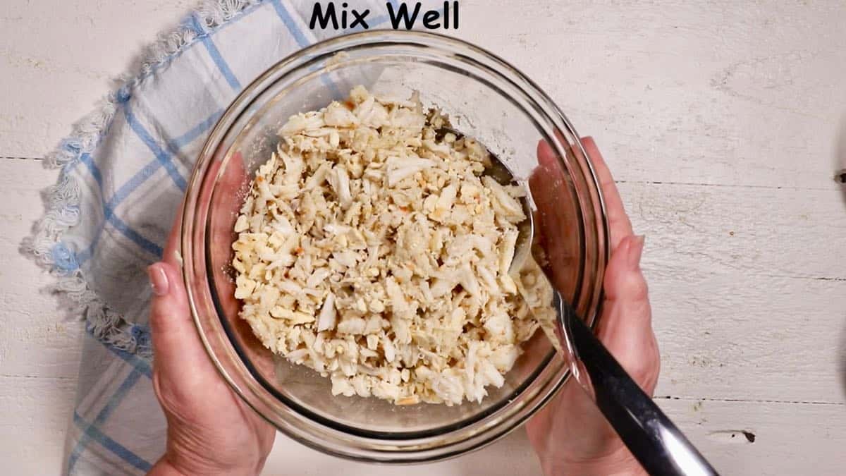 Crab meat and crushed saltines in a clear glass bowl.