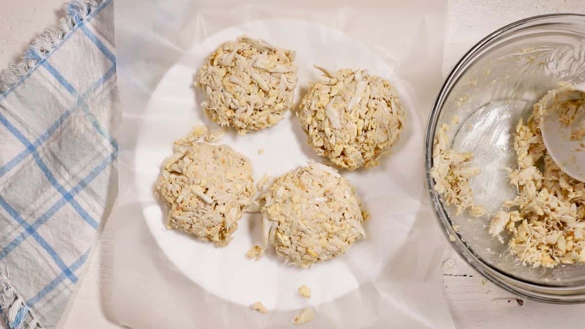 Four crab cakes on a white plate.