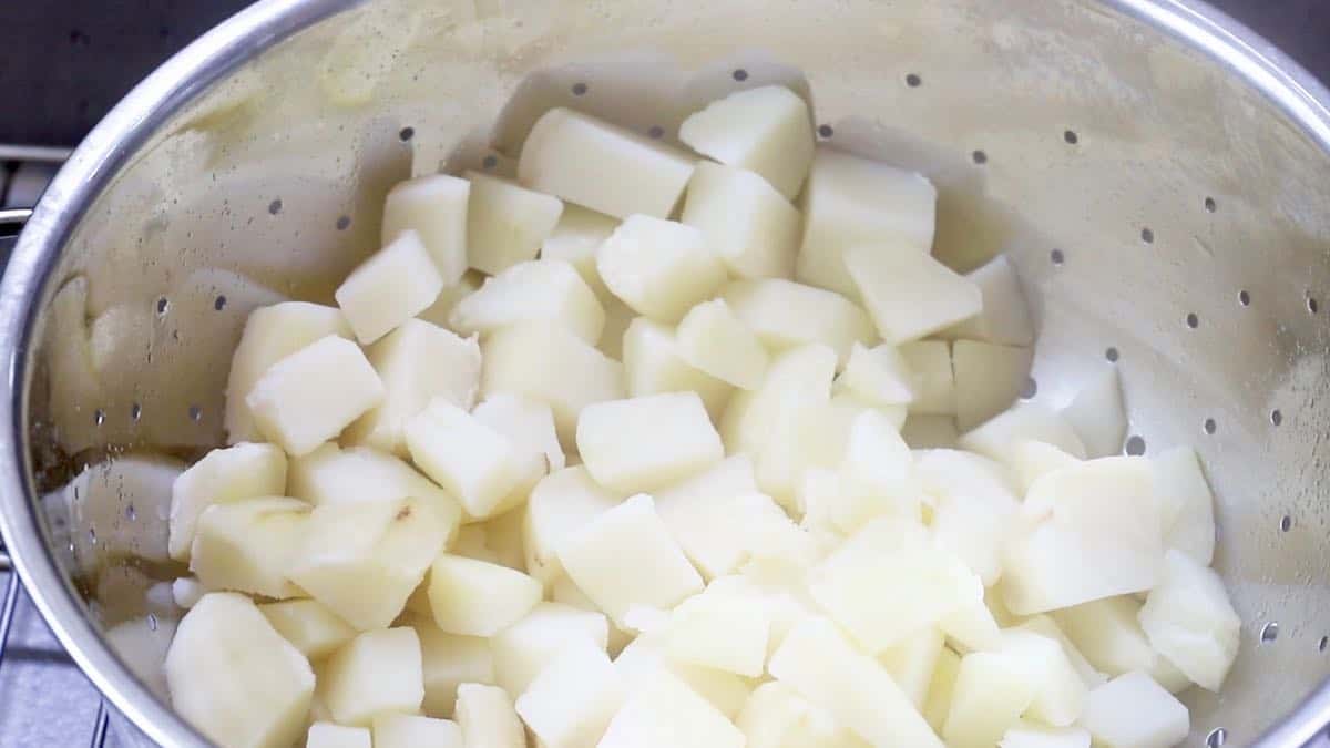 Cubed potatoes draining in a colander.