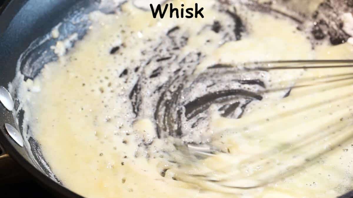 Whisking flour and butter together in a skillet.