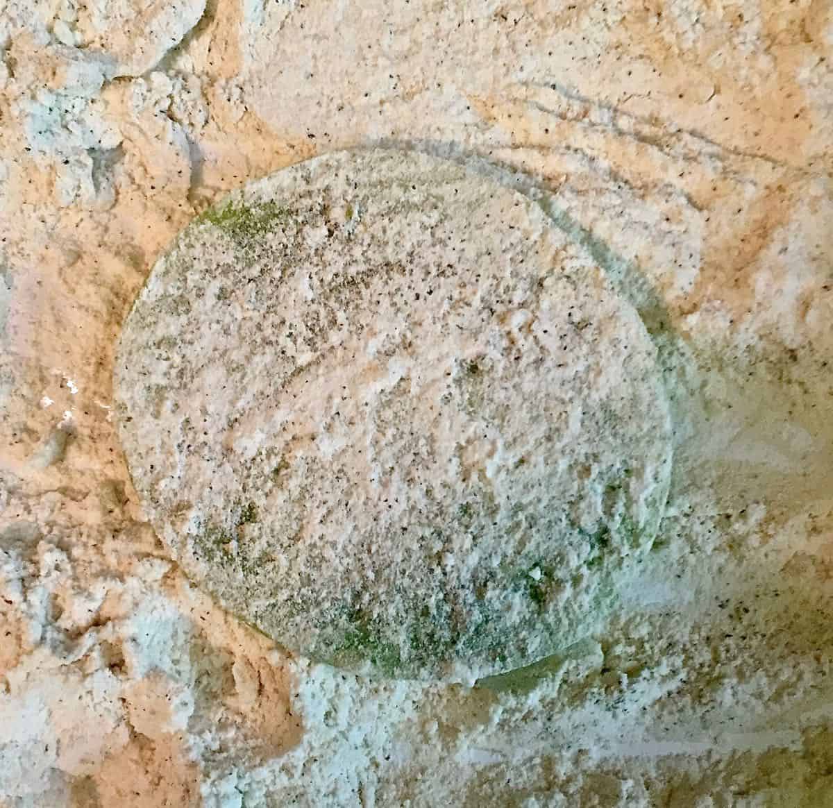 A slice of tomato in a bowl of flour. 