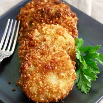 Three slices of green tomatoes which have been coated in panko and fried.