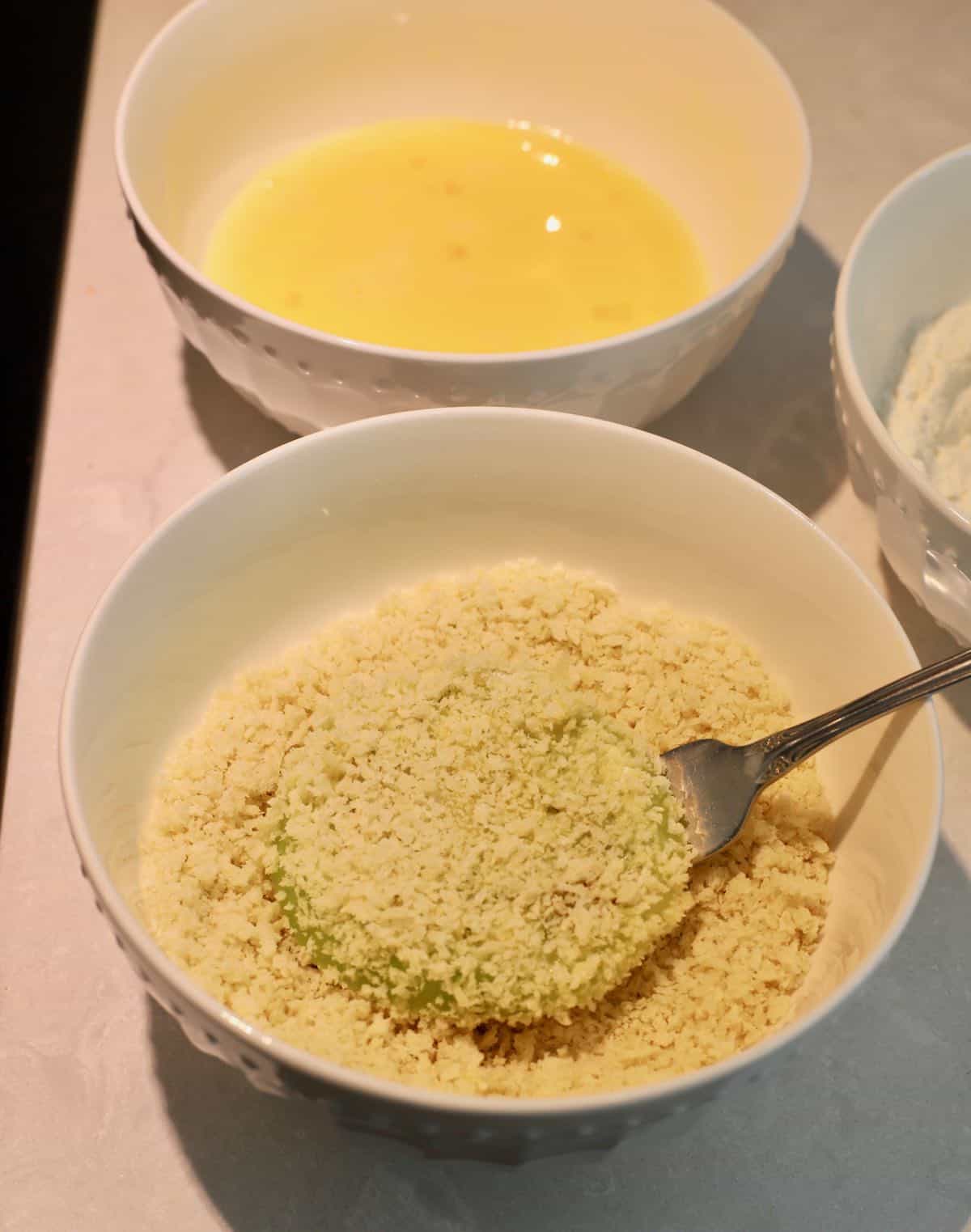 A bowl full of panko breadcrumbs with a tomato slice in it. 