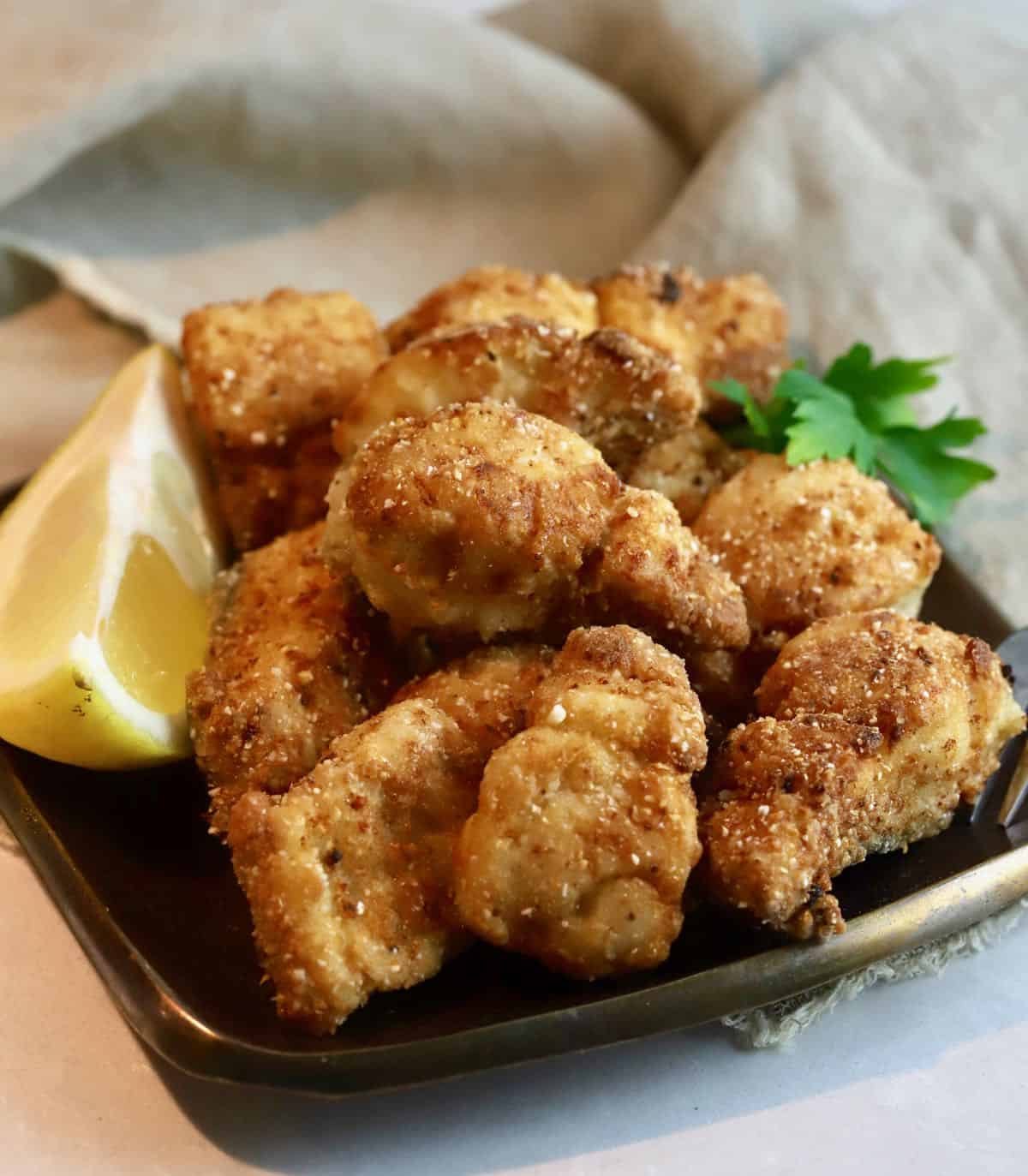 Fried mackerel nuggets on a bronze plate.