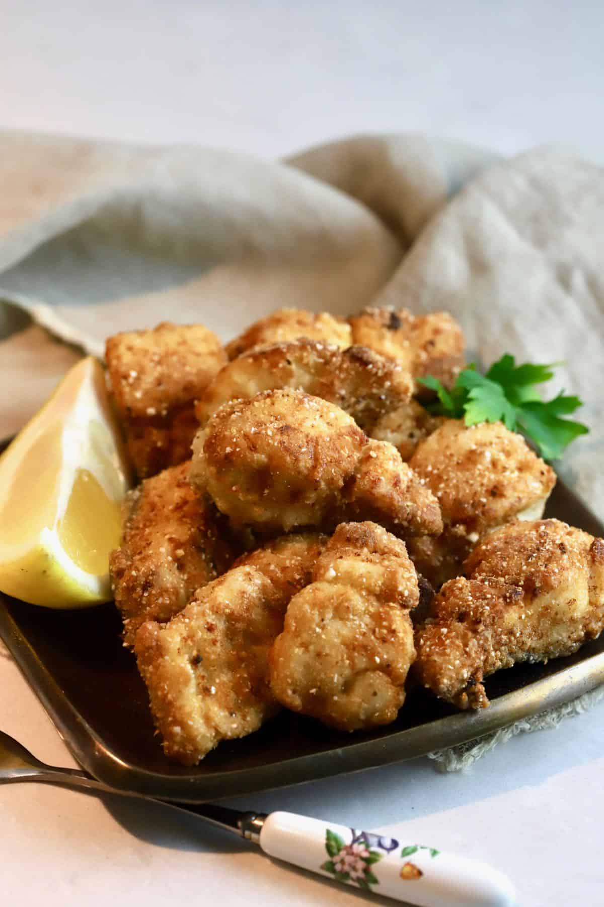 A bronze plate with fried fish nuggets.