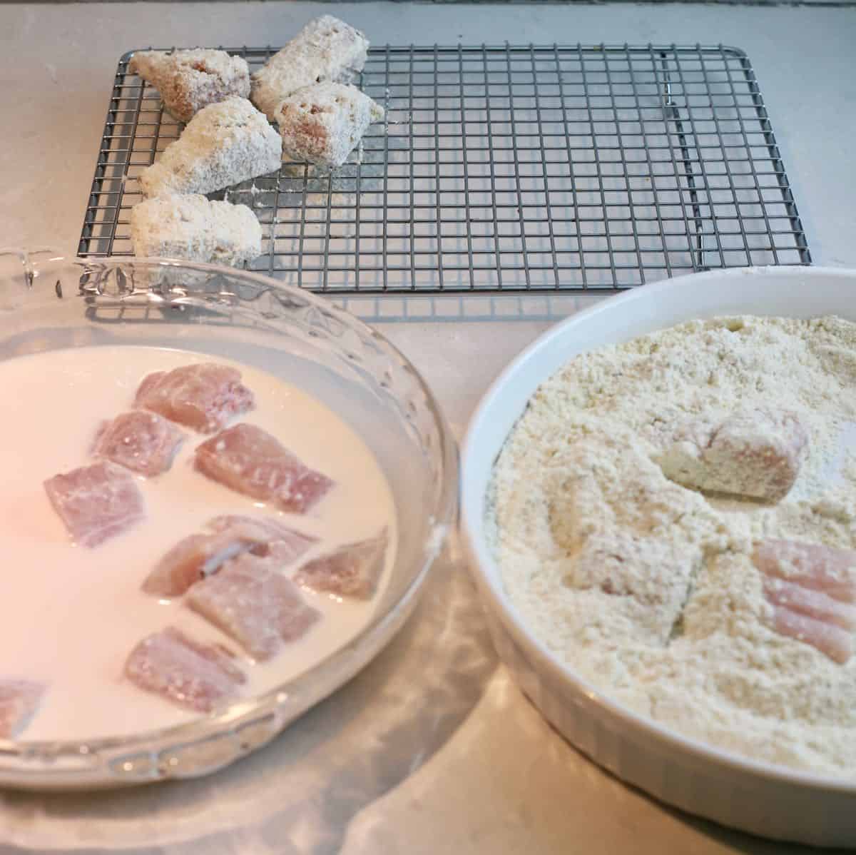 A bowl with buttermilk and fish pieces and a bowl of cornmeal mixture.