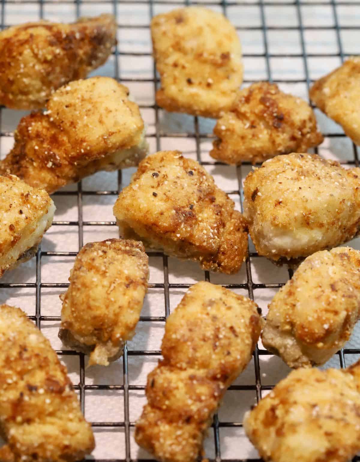 Pieces of fried fish draining on a wire rack.