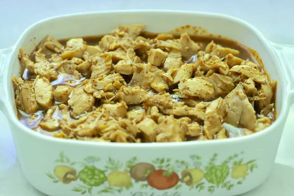 Cut up chicken marinating in a white dish. 