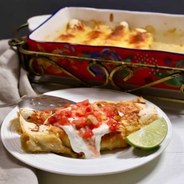 Enchiladas on a plate topped with sour cream and salsa.