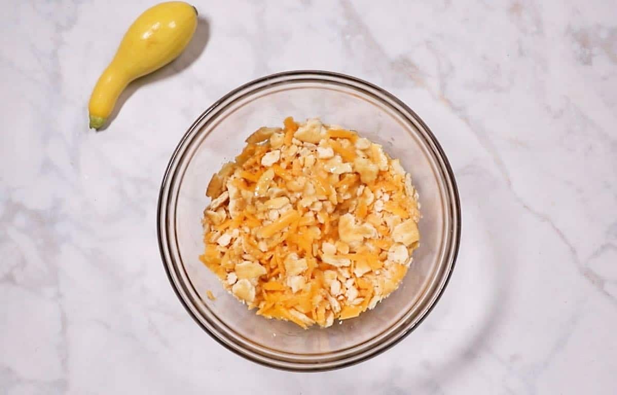 Crushed Ritz crackers, butter and cheese in a bowl. 
