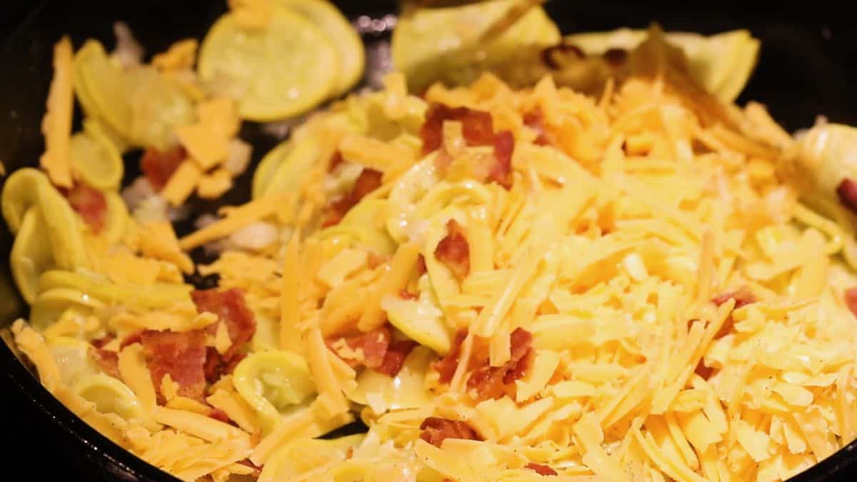 Squash, bacon, and cheese in a skillet. 