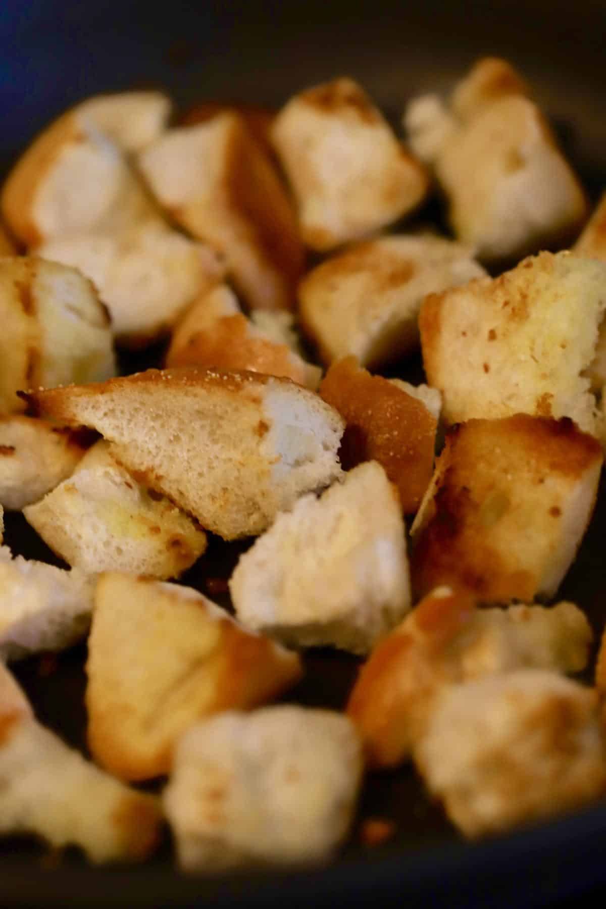 Toasting bread cubes in olive oil in a skillet.