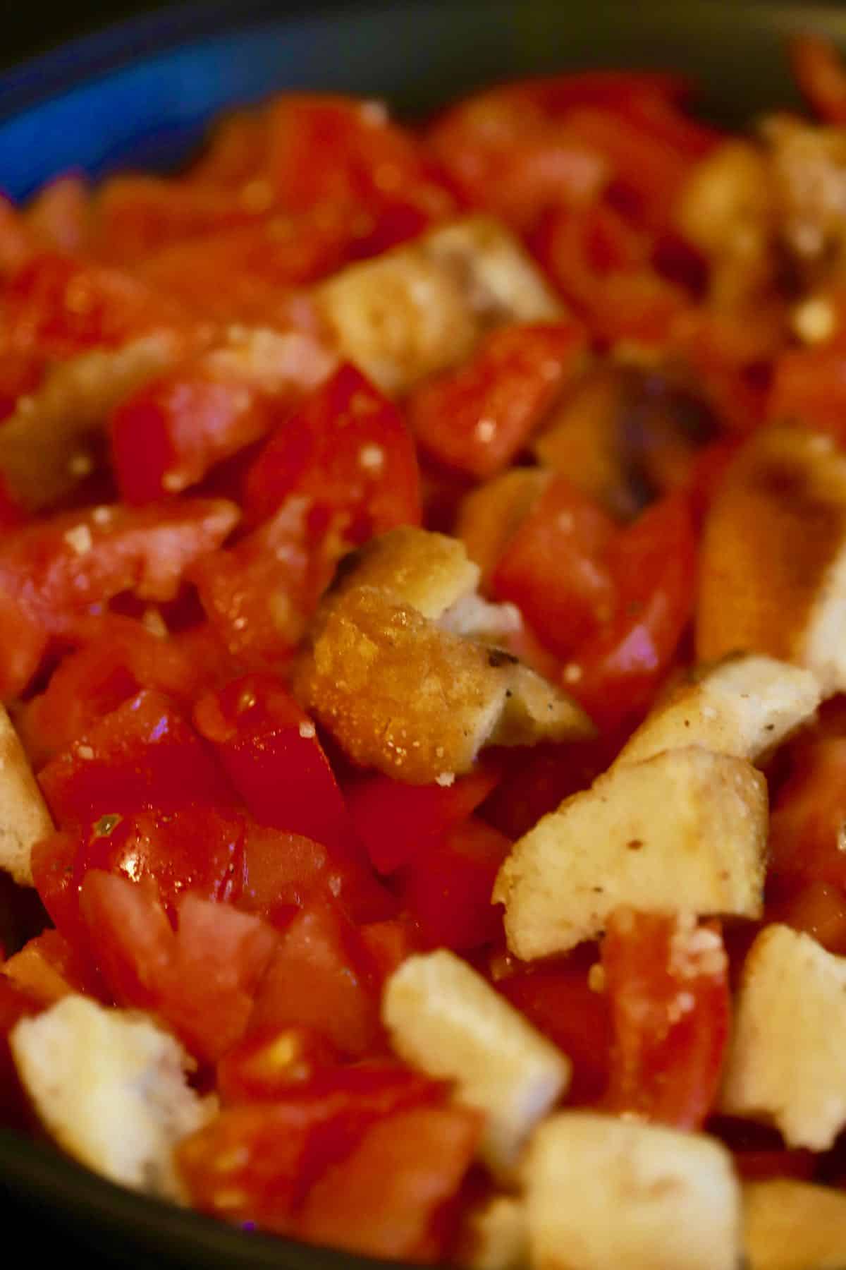 Toasted bread cubes mixed with tomatoes in a skillet.