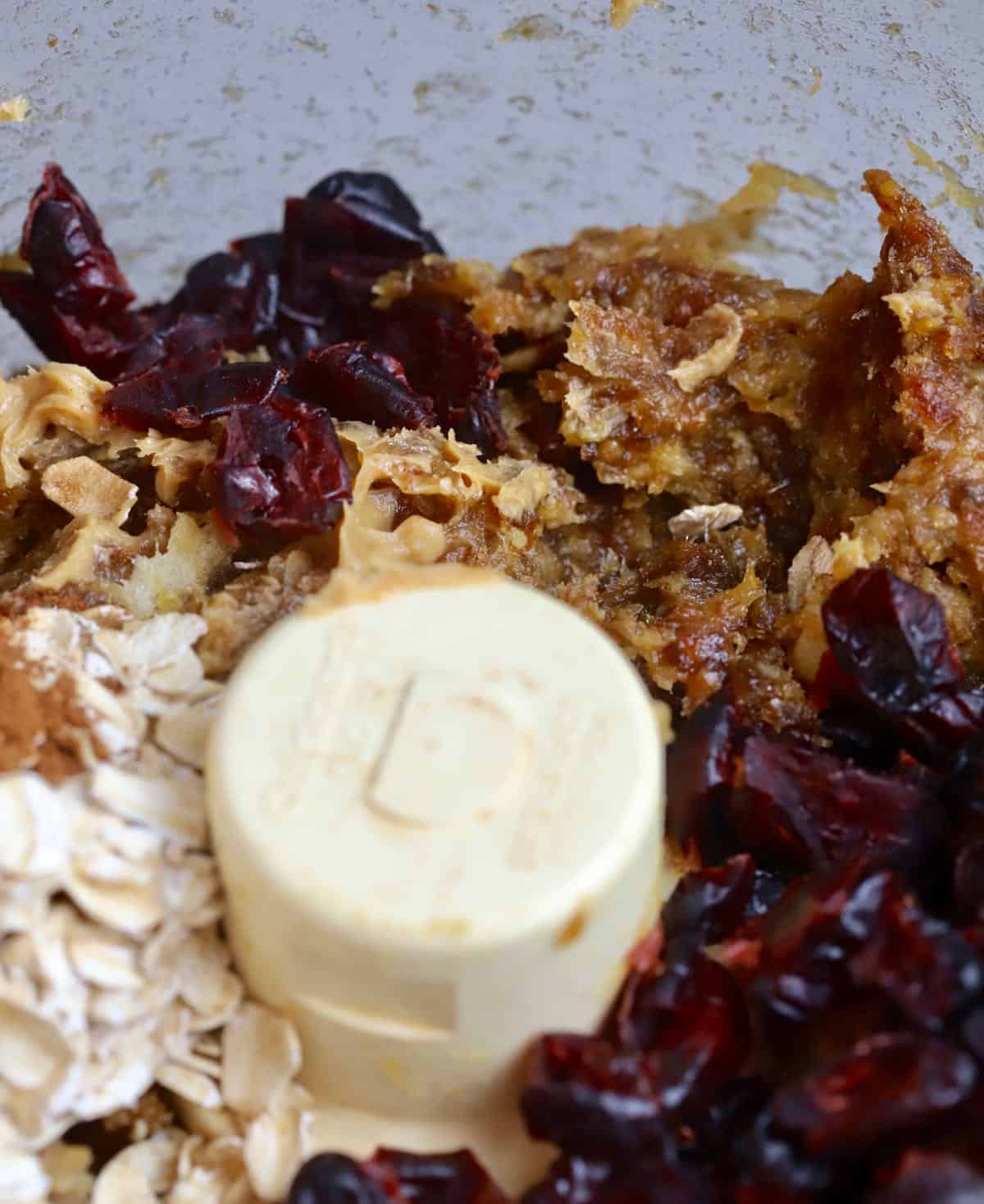 Chopped dates, oatmeal, dried cranberries and peanut butter in the bowl of a food processor. 