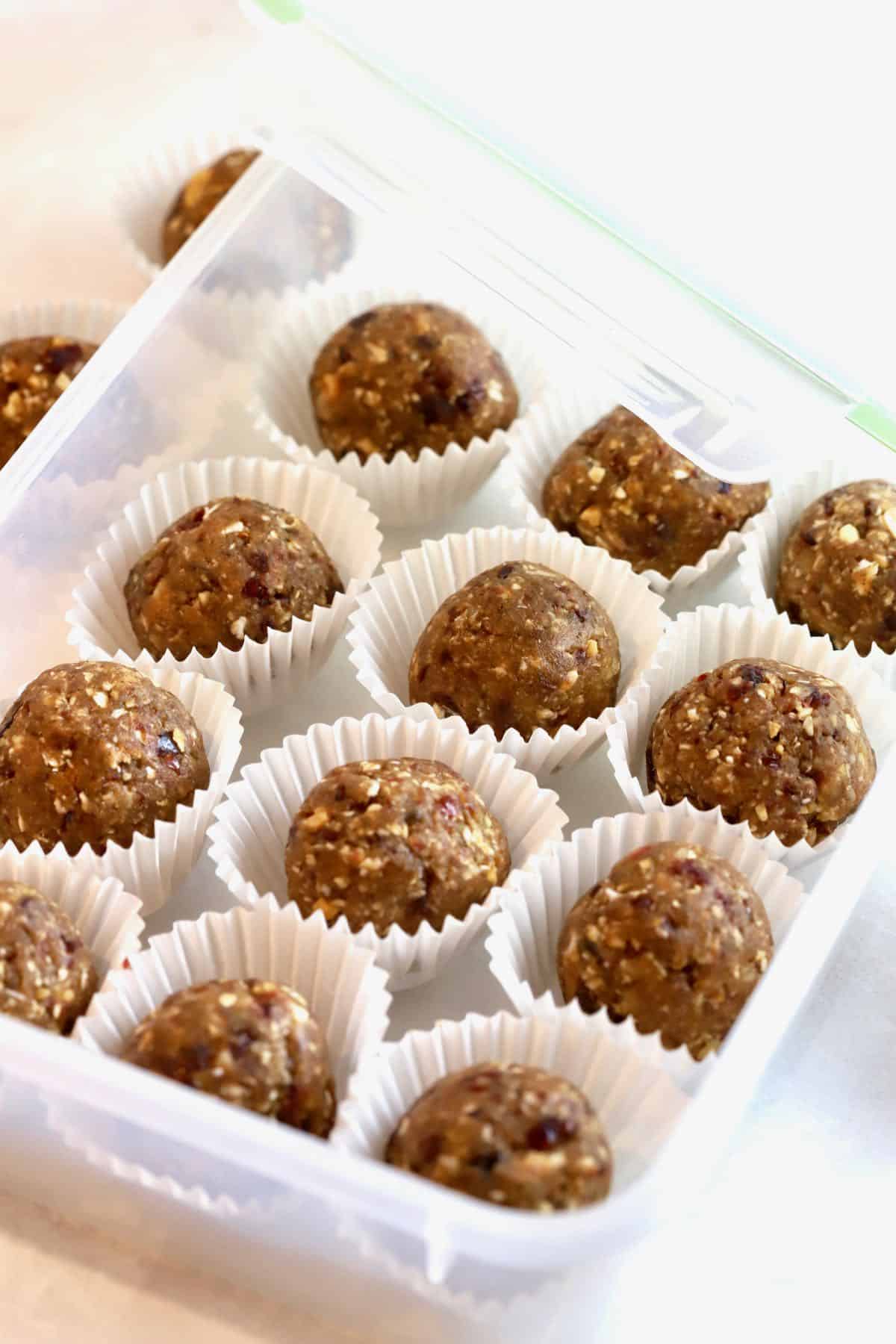 A plastic storage box full of the oatmeal energy balls in muffin liners. 