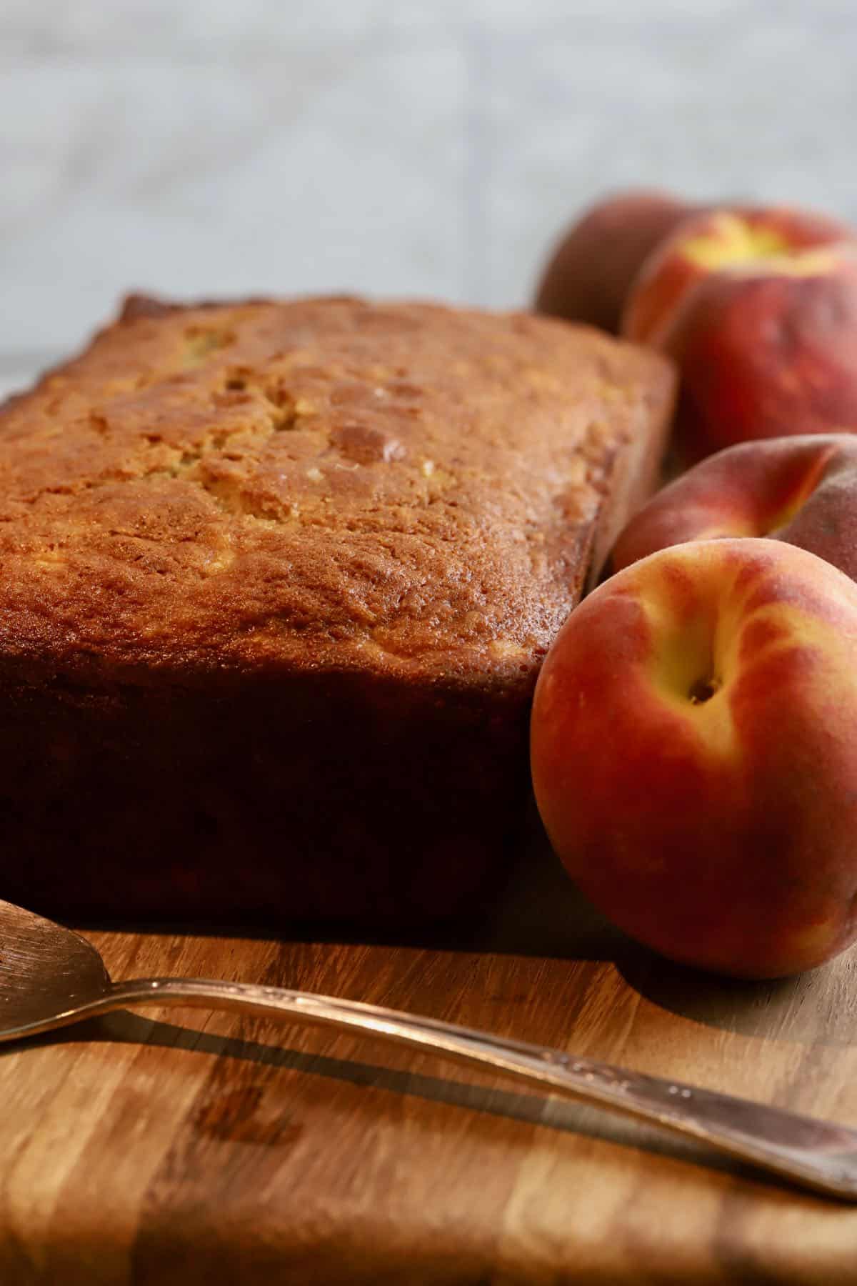 A loaf of peach bread on a wooden cutting board. 