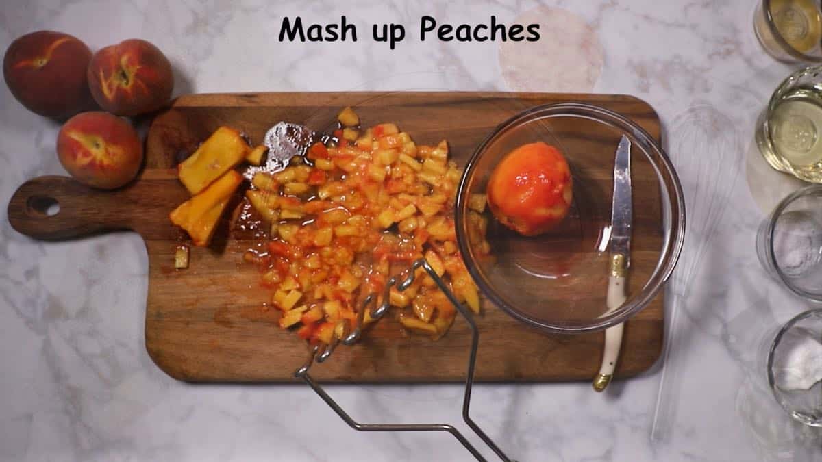 Mashing pieces of peaches on a wooden cutting board. 