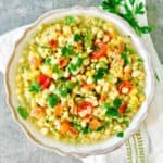 A large white bowl full of white acre peas and corn.