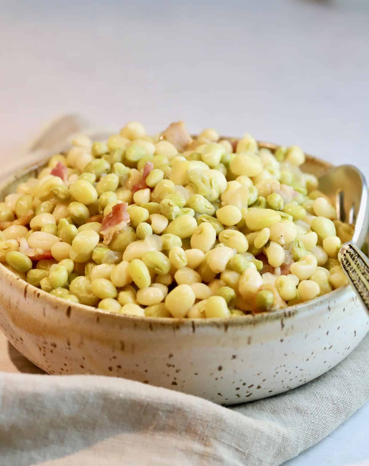 A brown and white pottery bowl full of Southern peas. 