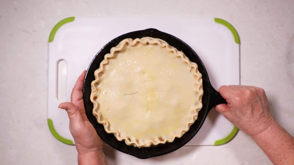 A cast-iron-skillet with an unbaked tomato pie. 