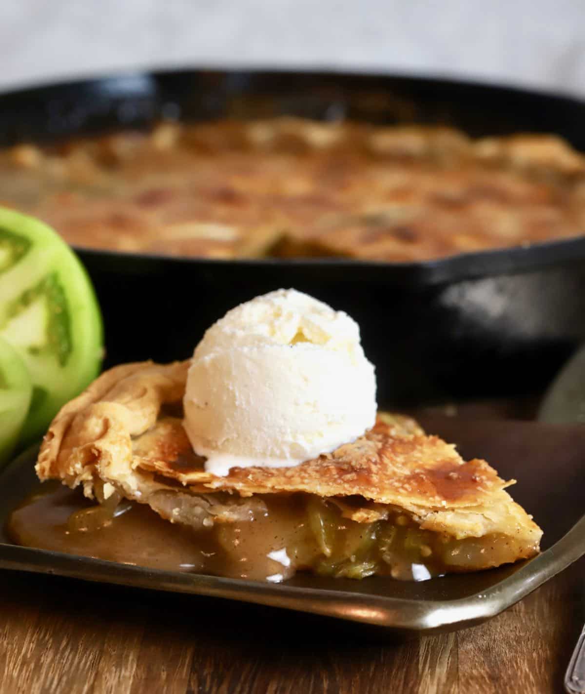 A slice of green tomato pie topped with a. scoop of ice cream